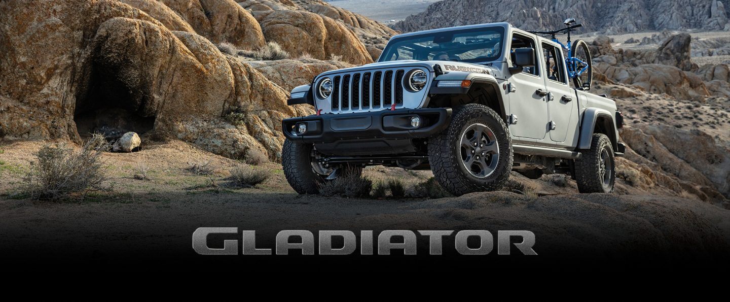 The 2022 Jeep Gladiator Rubicon towing an enclosed trailer on a snowy mountain road. The Presidents Day Event logo.