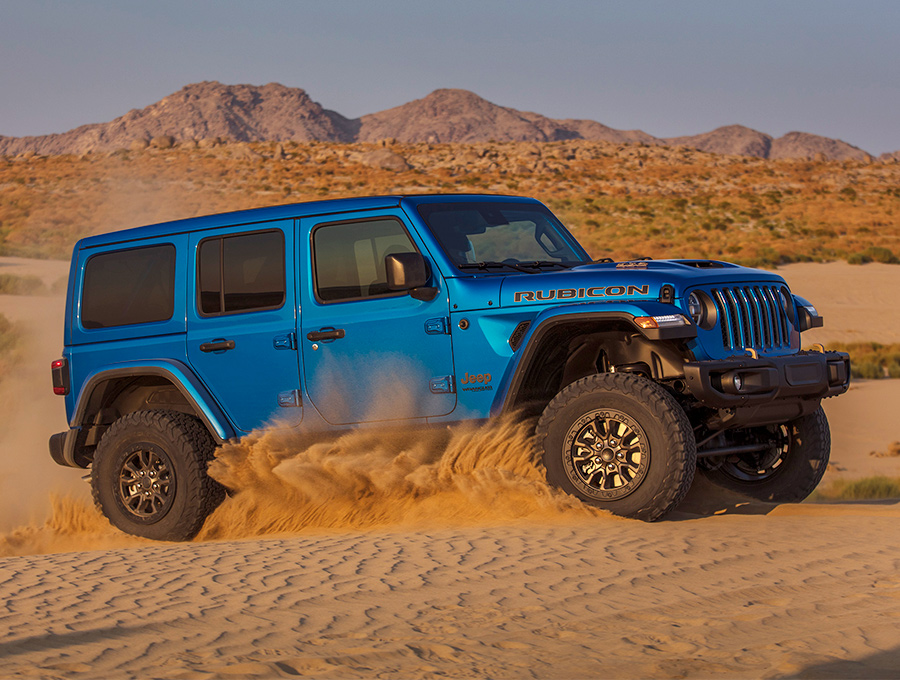 The 2021 Jeep Wrangler Rubicon 392 being driven on desert terrain, churning up sand from its wheels.
